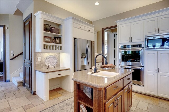 kitchen featuring a center island with sink, sink, white cabinetry, and stainless steel appliances