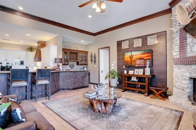 living room with crown molding, a stone fireplace, and ceiling fan