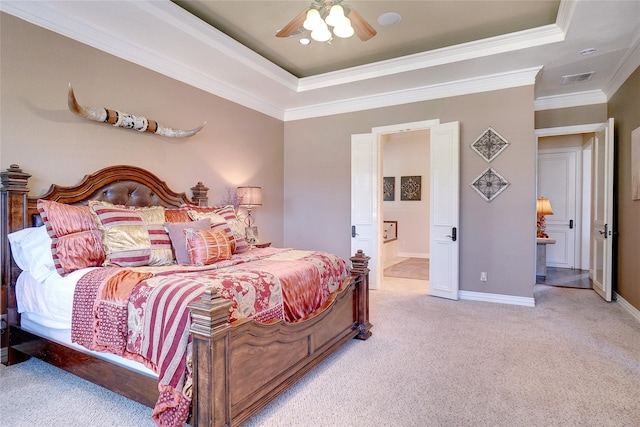 carpeted bedroom featuring ornamental molding, ensuite bathroom, a tray ceiling, and ceiling fan