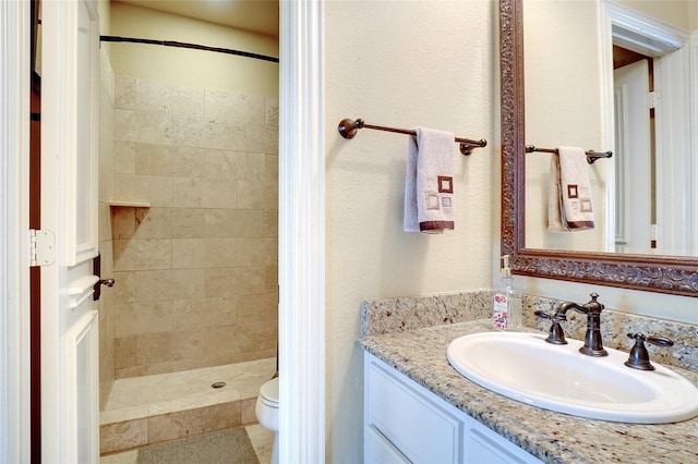 bathroom featuring vanity, toilet, and tiled shower