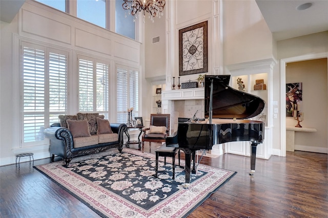 living area with a towering ceiling, an inviting chandelier, and dark hardwood / wood-style floors