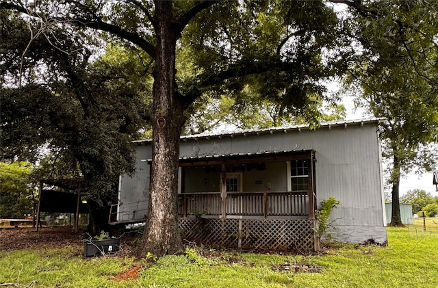 back of property featuring covered porch and a yard