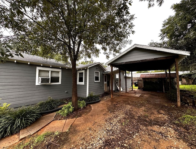 exterior space featuring a carport, cooling unit, and dirt driveway