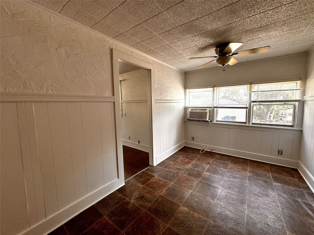 interior space with ceiling fan, cooling unit, and wood walls