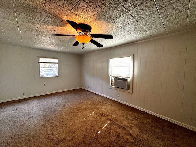 spare room with carpet, ceiling fan, cooling unit, and wood walls