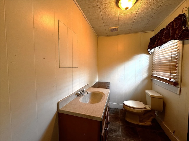 bathroom with tile patterned floors, wood walls, vanity, and toilet