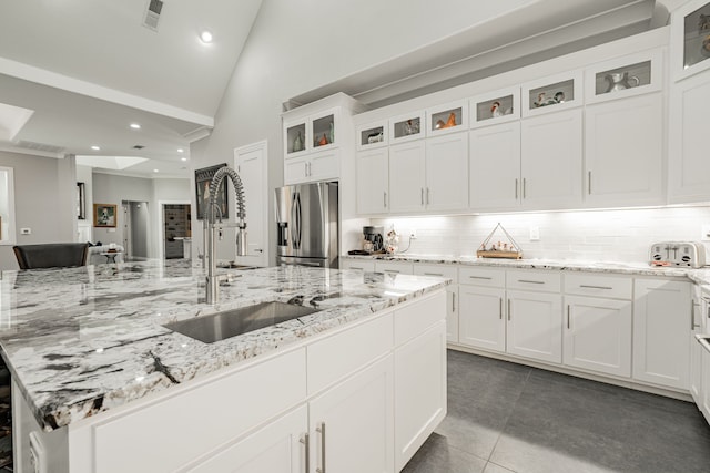 kitchen featuring stainless steel fridge with ice dispenser, light stone countertops, white cabinets, backsplash, and sink