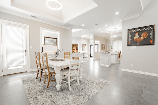 dining area with an inviting chandelier, plenty of natural light, a raised ceiling, and crown molding