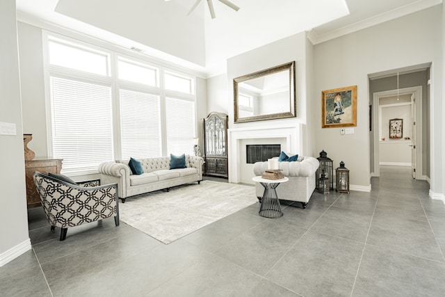 living room with tile flooring, a high ceiling, ceiling fan, and ornamental molding