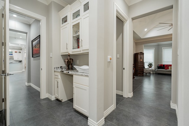 hallway with dark tile flooring and vaulted ceiling