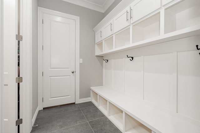 mudroom featuring dark tile flooring and crown molding