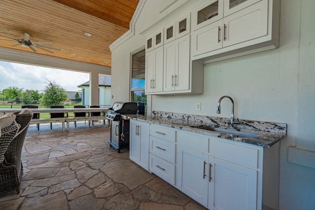 kitchen featuring ceiling fan, light stone countertops, wood ceiling, white cabinets, and sink