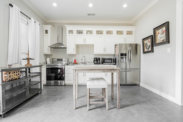 kitchen with crown molding, wall chimney exhaust hood, white cabinets, sink, and appliances with stainless steel finishes