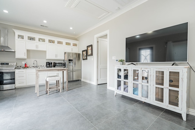 kitchen featuring appliances with stainless steel finishes, wall chimney range hood, sink, and white cabinetry