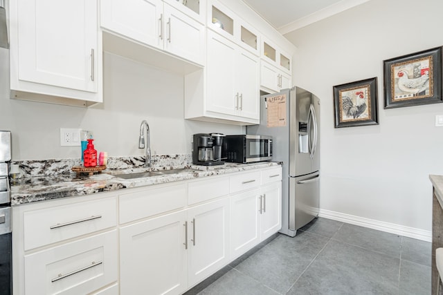 kitchen with light stone counters, tile flooring, white cabinets, sink, and appliances with stainless steel finishes