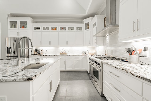 kitchen with wall chimney range hood, stainless steel appliances, white cabinets, and tasteful backsplash