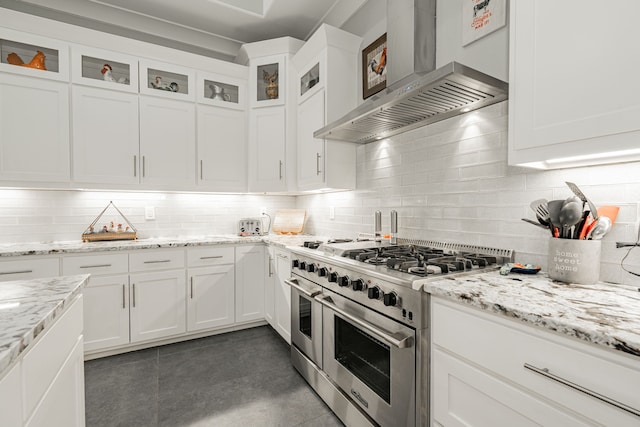 kitchen featuring white cabinets, wall chimney exhaust hood, double oven range, and tasteful backsplash