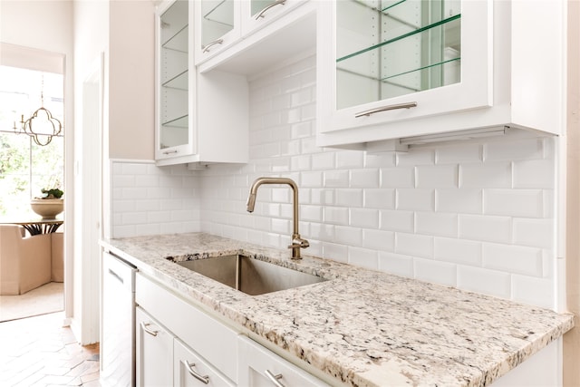 kitchen with light stone countertops, tasteful backsplash, sink, dishwasher, and white cabinets