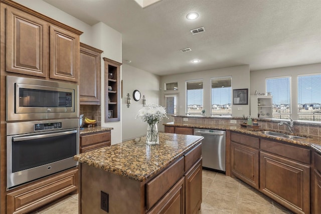 kitchen featuring a kitchen island, a sink, visible vents, appliances with stainless steel finishes, and decorative backsplash