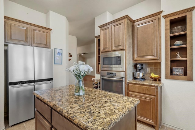 kitchen featuring decorative backsplash, a kitchen island, light stone countertops, stainless steel appliances, and light tile patterned flooring