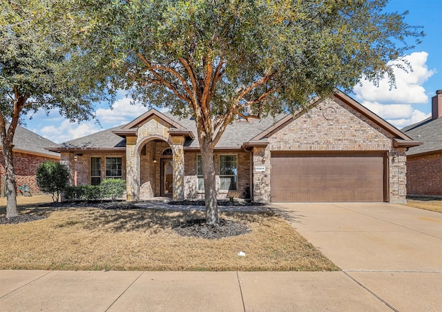 single story home featuring a garage, driveway, brick siding, and a front yard