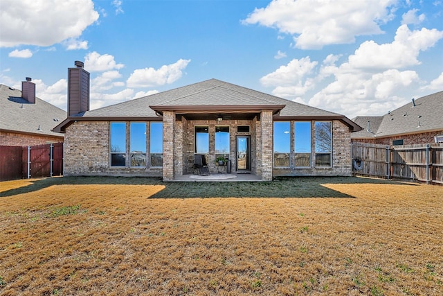 rear view of house with brick siding, a yard, a patio, a shingled roof, and a fenced backyard