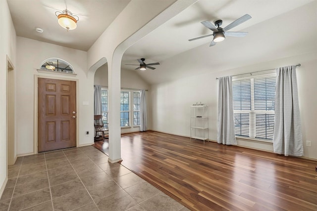 foyer with a wealth of natural light, arched walkways, a ceiling fan, and wood finished floors