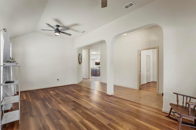 living area featuring a ceiling fan, arched walkways, and wood finished floors