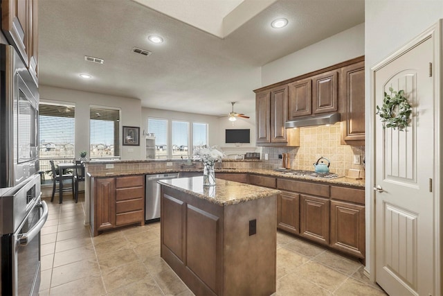 kitchen featuring stainless steel appliances, visible vents, decorative backsplash, a peninsula, and under cabinet range hood