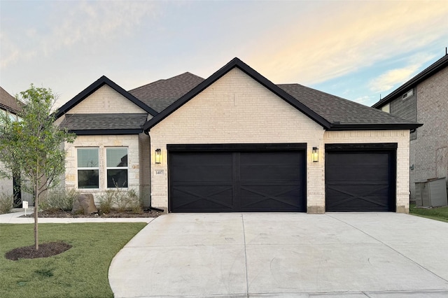 view of front of home featuring an attached garage, brick siding, a shingled roof, concrete driveway, and a front yard