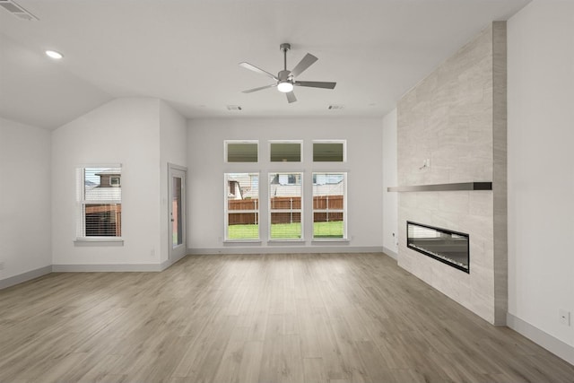 unfurnished living room with a ceiling fan, baseboards, visible vents, a tile fireplace, and light wood-style floors