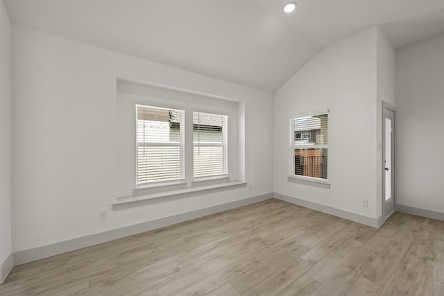 empty room featuring lofted ceiling, light wood-style flooring, and baseboards