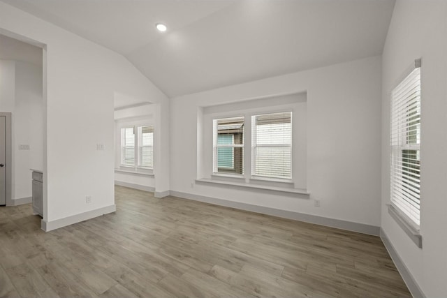 unfurnished room with recessed lighting, baseboards, light wood-style flooring, and vaulted ceiling