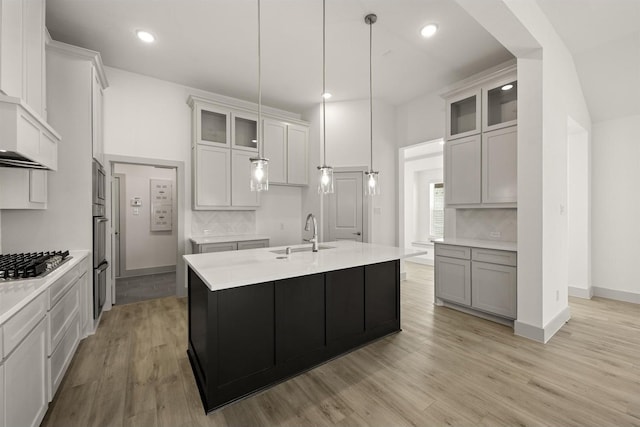 kitchen featuring stainless steel appliances, glass insert cabinets, light countertops, and a sink