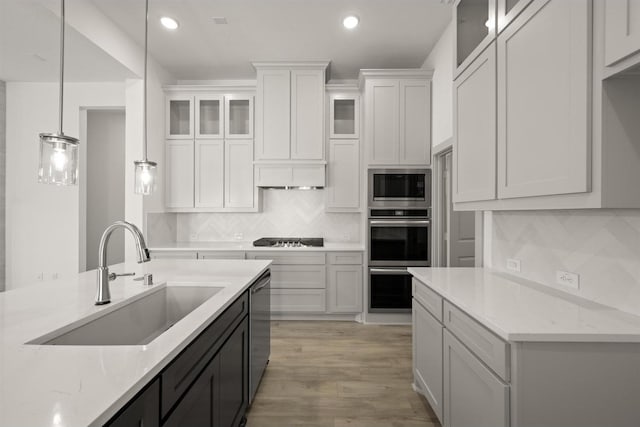 kitchen with a sink, appliances with stainless steel finishes, white cabinetry, tasteful backsplash, and light wood-type flooring