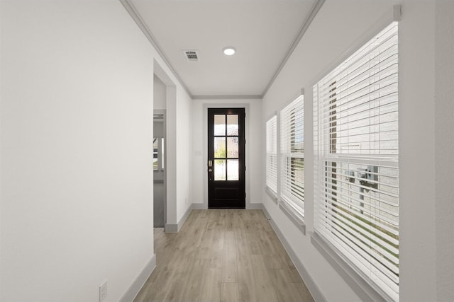 doorway to outside with ornamental molding, light wood-style floors, and baseboards