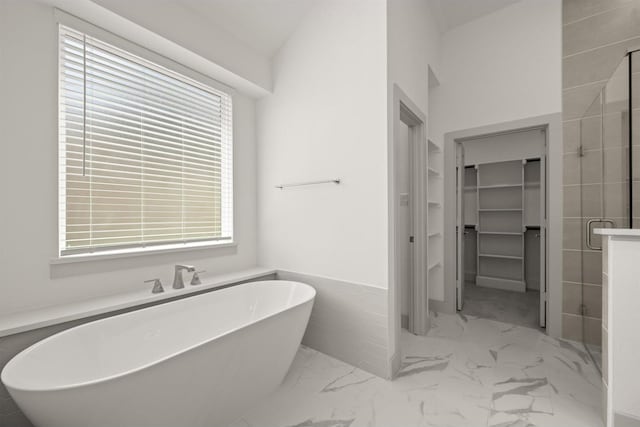 bathroom featuring a walk in closet, a shower stall, marble finish floor, and a freestanding bath