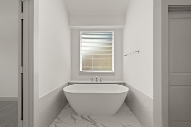 full bathroom featuring a wainscoted wall, a freestanding bath, and tile walls