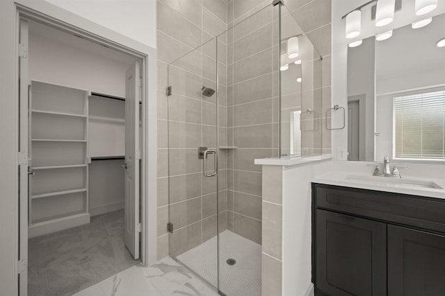 full bathroom featuring vanity, a spacious closet, marble finish floor, and a shower stall