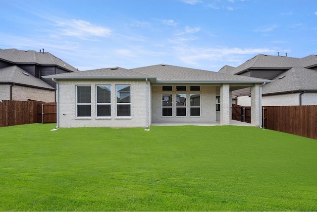 back of property with a yard, a fenced backyard, brick siding, and roof with shingles