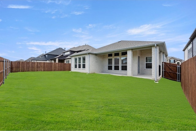 rear view of house featuring a lawn, a fenced backyard, and brick siding