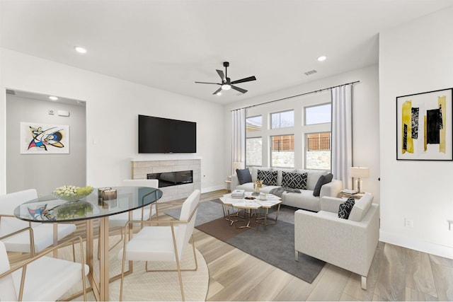 living area with baseboards, a tiled fireplace, recessed lighting, wood finished floors, and a ceiling fan