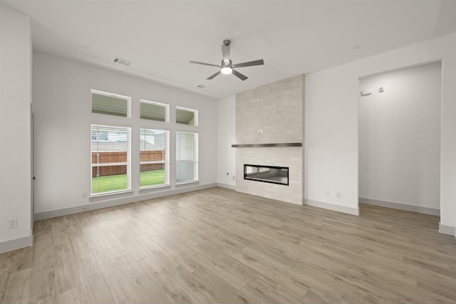 unfurnished living room with visible vents, baseboards, light wood-style flooring, a fireplace, and a ceiling fan