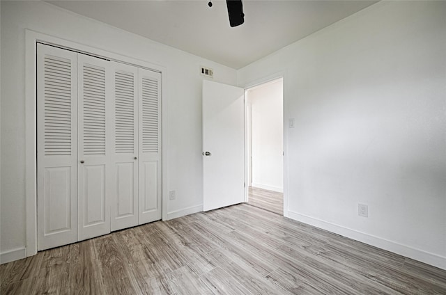 unfurnished bedroom featuring ceiling fan, a closet, and light hardwood / wood-style flooring