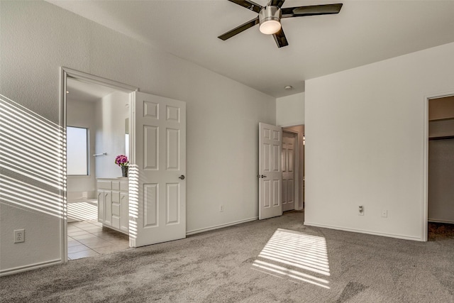 unfurnished bedroom with ceiling fan, light colored carpet, and a walk in closet