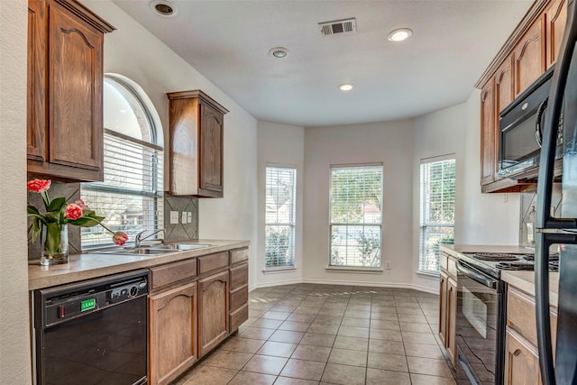 kitchen featuring light tile patterned floors, decorative backsplash, black appliances, and sink