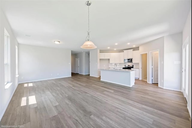 unfurnished living room with recessed lighting, a sink, visible vents, baseboards, and light wood finished floors