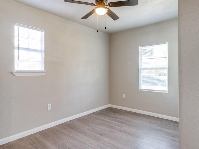 empty room featuring a wealth of natural light, ceiling fan, and light wood-type flooring