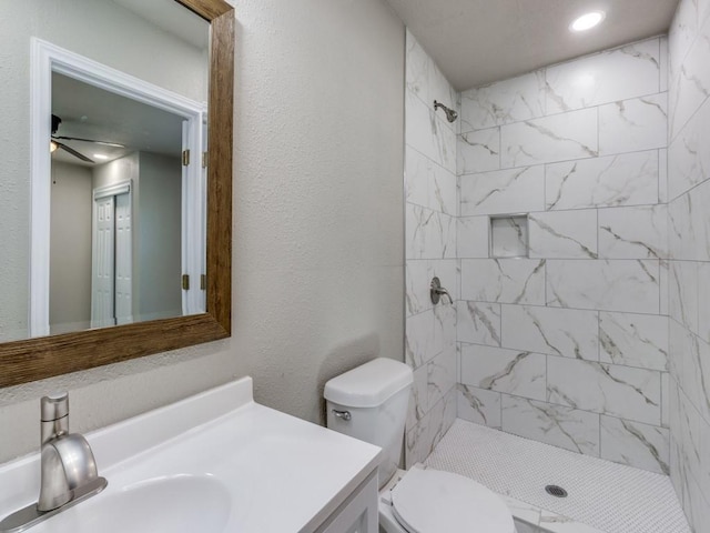 bathroom featuring vanity, ceiling fan, toilet, and tiled shower