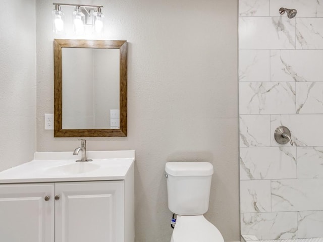 bathroom featuring tiled shower, vanity, and toilet